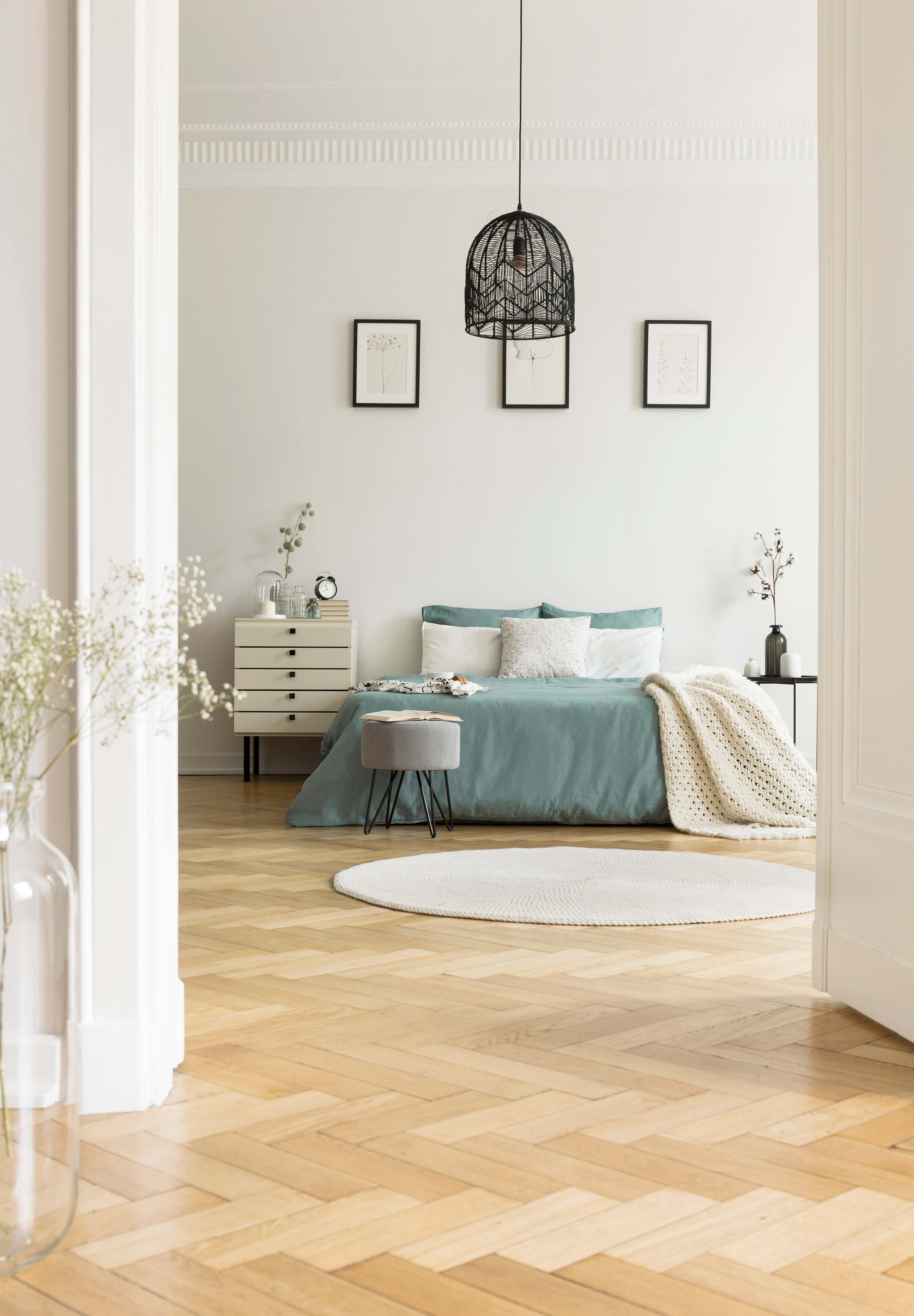 Modernes Wohnzimmer mit grün gestrichener Wand, heller Couch, Zierkissen und kleinen Pflanzen